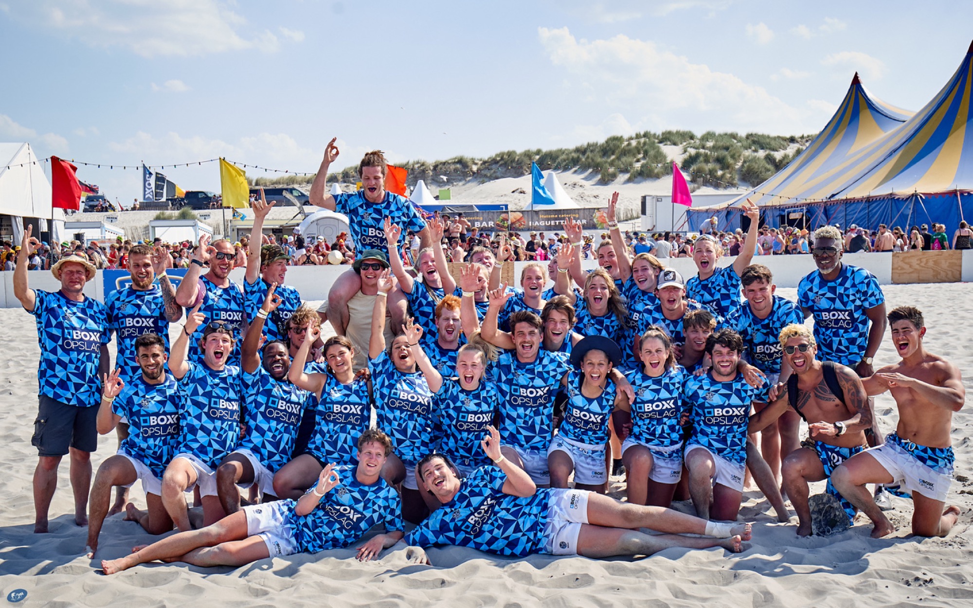 Team in branded kit celebrating at a beach rugby event